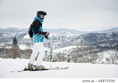 Male skier standing on snowy hill in mountains. 68870390
