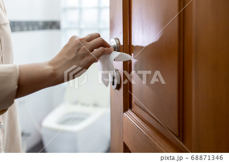 Hand with door handle,girl open the bathroom door,woman using tissue paper to touch the door knob instead of hands to prevent infection of Covid-19,outbreak of Coronavirus,pandemic,contagious diseases 68871346