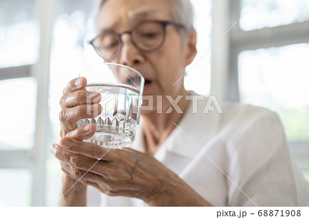 Senior woman holding glass of water,hand shaking while drinking water,elderly patient with hands tremor uncontrolled body tremors,symptom of essential tremor,parkinson's disease,neurological disorders Senior woman holding glass of water,hand shaking while drinking water,elderly patient with hands tremor uncontrolled body tremors,symptom of essential tremor,parkinson's disease,neurological disorders 68871908