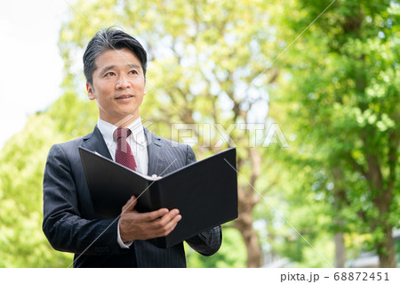 新緑の屋外で資料を見るビジネスマン 新緑の屋外で資料を見るビジネスマン 68872451