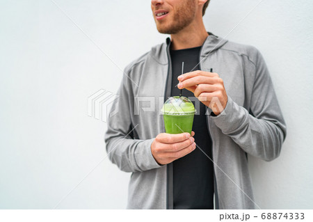 Healthy young man drinking green juice smoothie cup as weight loss detox meal replacement diet. Spinach protein shake for morning breakfast 68874333