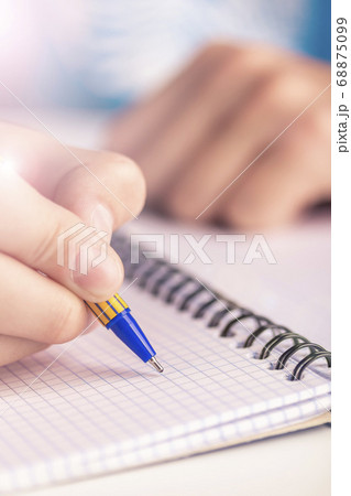 Teen writes black yellow pen in a checkered notebook. Spiral bound Teen writes black yellow pen in a checkered notebook. Spiral bound 68875099