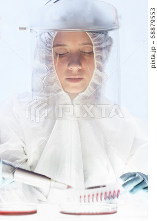 Female scientist working in the corona virus vaccine development laboratory research with a highest degree of protection gear. Female scientist working in the corona virus vaccine development laboratory research with a highest degree of protection gear. 68879553