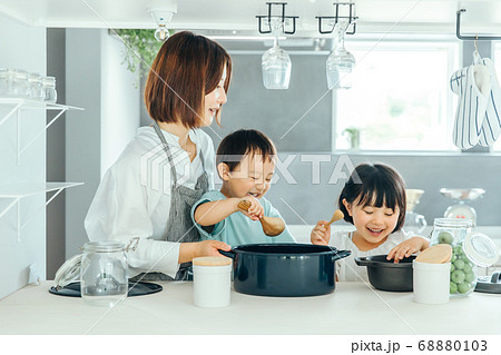 新築のリビングで母親が子供二人に料理を教えている　fmaily kids 子育て 68880103