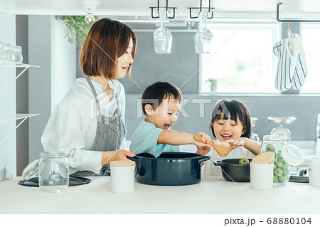 新築のリビングで母親が子供二人に料理を教えている　fmaily kids 子育て 68880104