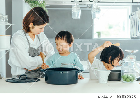 キッチンでお母さんが料理を教えながらいたずらしている子供に叱っている Kids Kitchen Faの写真素材