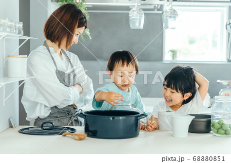 キッチンでお母さんが料理を教えながらいたずらしている子供に叱っている Kids Kitchen Faの写真素材