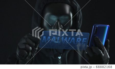 Hacker wearing black mask pulls MALWARE tab from a smartphone. Hacking concept 68882168