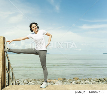 female doing stretching exercise for legs, Young fitness healthy woman warm up before running or jogging in the beach in sunshine on beautiful summer day. Sport fitness training outdoor concept. female doing stretching exercise for legs, Young fitness healthy woman warm up before running or jogging in the beach in sunshine on beautiful summer day. Sport fitness training outdoor concept. 68882400