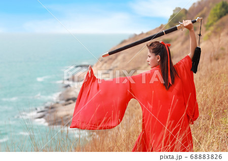portrait of young and beautiful woman wearing red chinese warrior costume with black sword 68883826