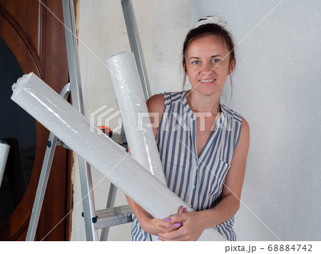 Woman in rolls of Wallpaper in the room. Preparation for repairs in the apartment. Woman in rolls of Wallpaper in the room. Preparation for repairs in the apartment. 68884742