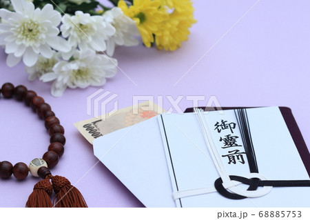 菊と一緒に置かれた香典袋とお金 68885753