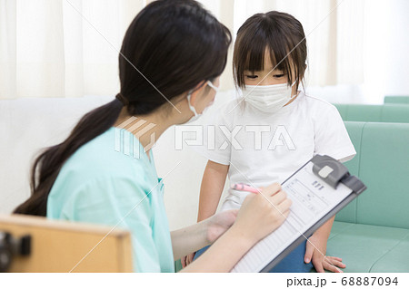 病院で診察する前に問診を受ける女の子の写真素材