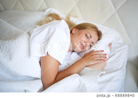 beautiful young woman sleeping on white bed 68889840