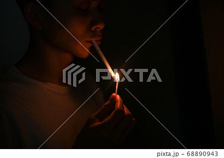 マッチでタバコに火をつける男性の写真素材