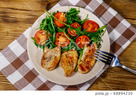 Fried chicken breast with salad of fresh arugula 68894230
