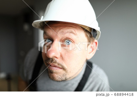 Surprised man in helmet looks closely and listens Surprised man in helmet looks closely and listens 68894418