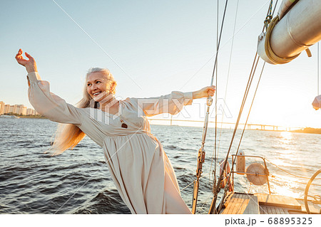 Smiling and happy mature woman enjoying sunset on a sailboat	 68895325