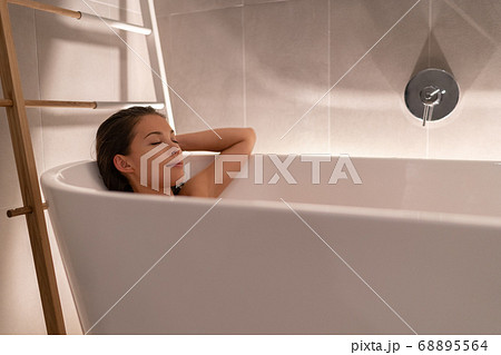 Luxury bathtub Asian woman relaxing in home spa taking a bath shower showering for total relaxation. Young lady body care wellness sleeping in warm water, winter pampering 68895564