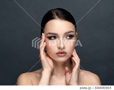 Young beautiful woman touching her face Young beautiful woman touching her face 68896964