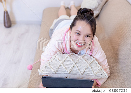 ソファーに寝転んでタブレットを見る女性 ソファーに寝転んでタブレットを見る女性 68897235