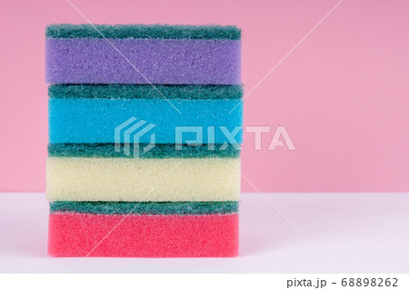 Multicolored sponges for washing dishes on top of each other on a pink background. Cleaning concept. 68898262
