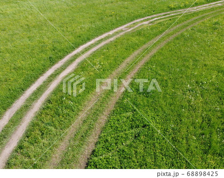 Summer field with tracks of car on grass. 68898425