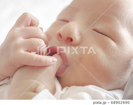 指しゃぶりしながら眠る生後11日目のかわいい赤ちゃんの写真素材