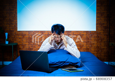 headache, tense young asian man working on laptop computer in bedroom at night headache, tense young asian man working on laptop computer in bedroom at night 68908357