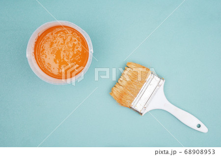 Paintbrush and bucket of ocher paint  68908953