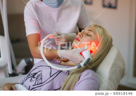 Beautiful female patient is getting a face skin treatment while lying at medical clinic Beautiful female patient is getting a face skin treatment while lying at medical clinic 68918546