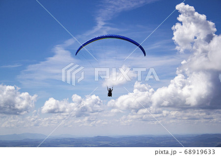Paraglider in the blue sky. The sportsman flying on a paraglider. 68919633