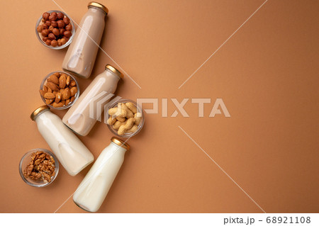 Bottles of nut non dairy milk on brown background flatlay Bottles of nut non dairy milk on brown background flatlay 68921108
