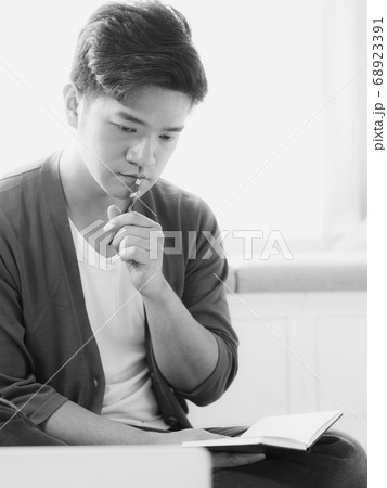 Young asian man writing in notebook. Young asian man writing in notebook. 68923391