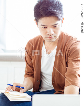 Young asian man writing in notebook. Young asian man writing in notebook. 68923394