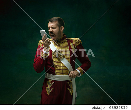 Young man as Nicholas II on dark green background. Retro style, comparison of eras concept. 68925336