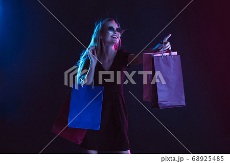 Portrait of young woman in neon light on dark backgound. The human emotions, black friday, cyber monday, purchases, sales, finance concept. 68925485