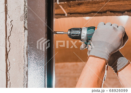 The carpenter drills holes in the wall and the The carpenter drills holes in the wall and the 68926099