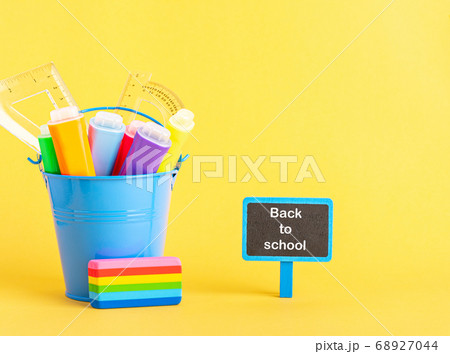 A metal bucket with highlighter marker pen and school ruler on a blue background. A metal bucket with highlighter marker pen and school ruler on a blue background. 68927044