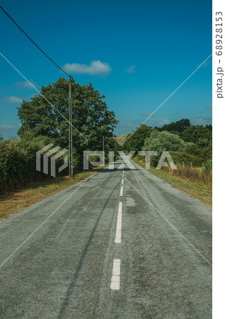 Deserted road passing through rural landscape 68928153