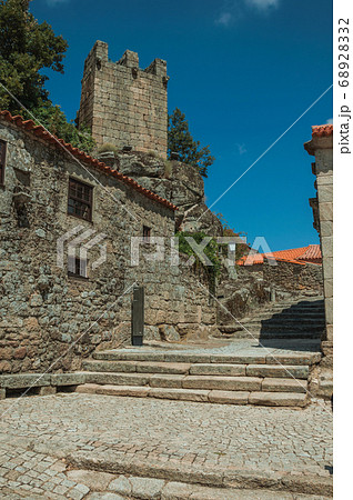 Houses made of stone with alley on slope and tower 68928332