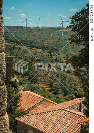 Wind turbines over hilly landscape and roofs 68928358