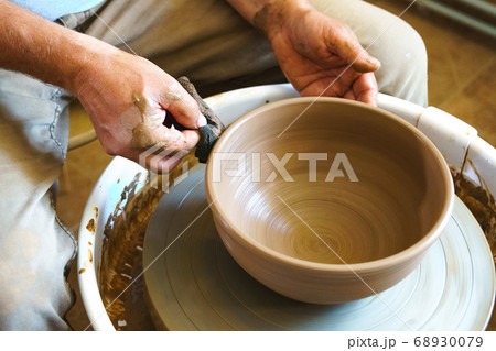 Potter working with clay on wheel. 68930079