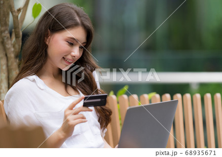Young woman sitting with smiley face using laptop 68935671