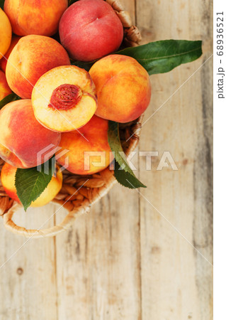 Peaches in a basket on a wooden background with a 68936521