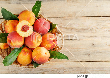 Fresh ripe peaches in a wicker basket on a wooden Fresh ripe peaches in a wicker basket on a wooden 68936522