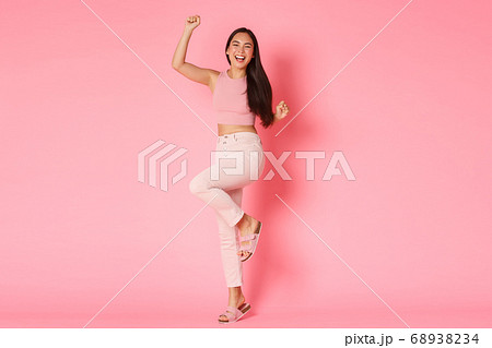 Fashion, beauty and lifestyle concept. Successful and winning asian female in stylish outfit, raising hands up cheerful, rejoicing as celebrating start of holidays, going on vacation, pink background Fashion, beauty and lifestyle concept. Successful and winning asian female in stylish outfit, raising hands up cheerful, rejoicing as celebrating start of holidays, going on vacation, pink background 68938234