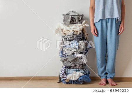 Standing woman legs near metal laundry basket full of dirty clothes and linen. Standing woman legs near metal laundry basket full of dirty clothes and linen. 68940039