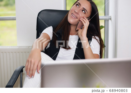 Cheerful woman sitting at her workplace in the office. She is thinking about her business. 68940803