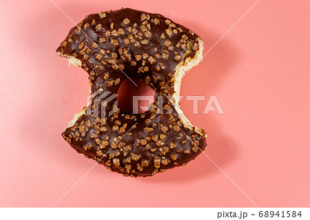 Bitten tasty chocolate donut on a pink background. Bitten tasty chocolate donut on a pink background. 68941584